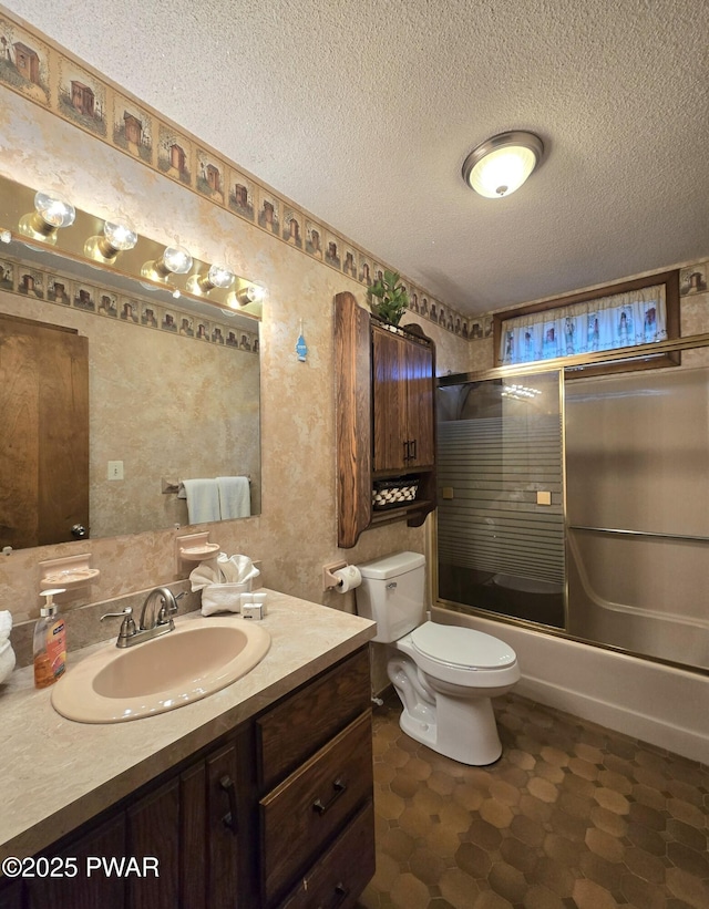 full bathroom featuring vanity, toilet, bath / shower combo with glass door, and a textured ceiling