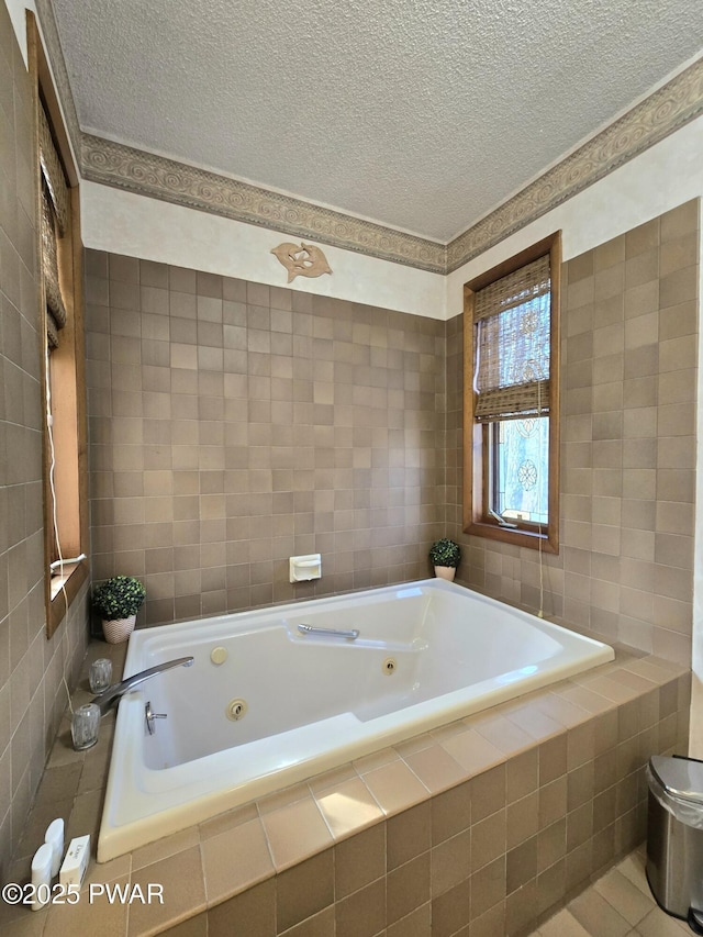 bathroom with a textured ceiling, tiled tub, and tile walls