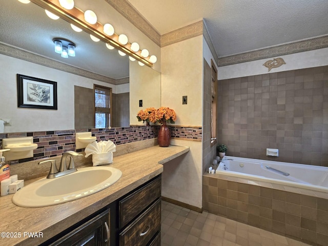 bathroom with a textured ceiling, tiled bath, and vanity