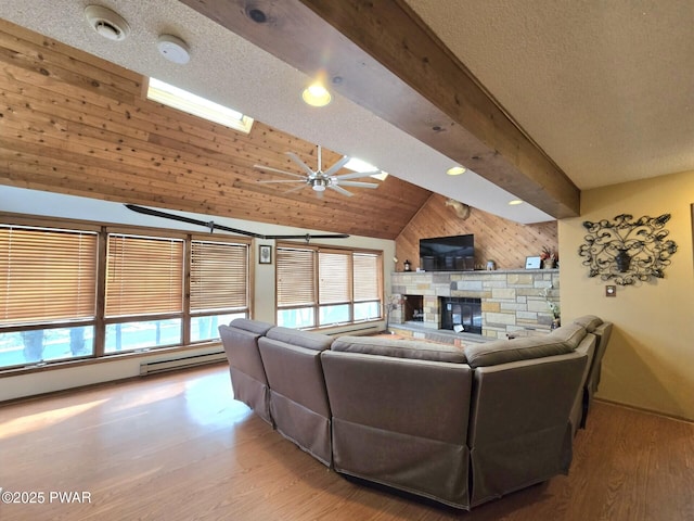 living room with wood-type flooring, ceiling fan, a fireplace, vaulted ceiling with beams, and wooden walls