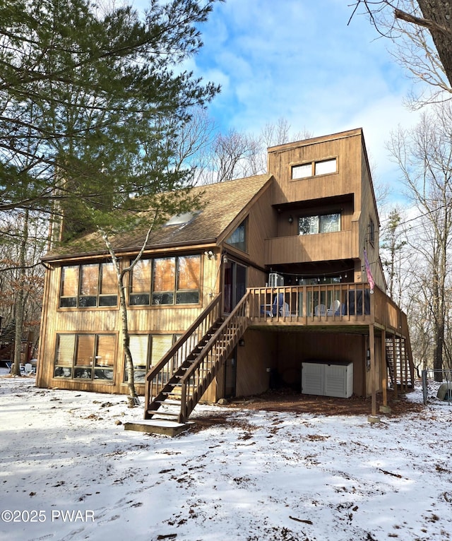 snow covered rear of property featuring a wooden deck