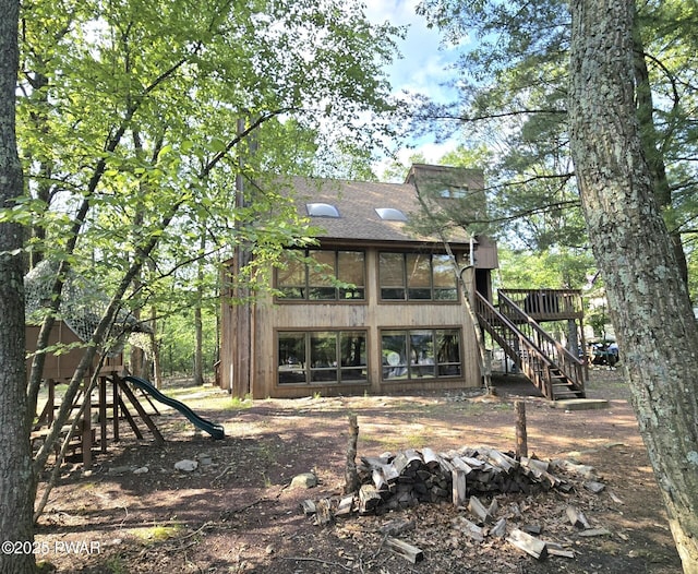 6128 Wales Ct, East Stroudsburg, PA 18301 - back of property with stairway, roof with shingles, a deck, a playground, and a sunroom