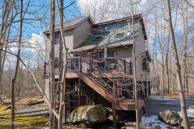 back of property featuring stairs, a shingled roof, and a wooden deck