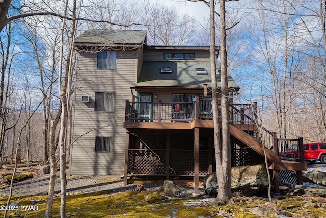 rear view of property featuring a deck, roof with shingles, and stairway