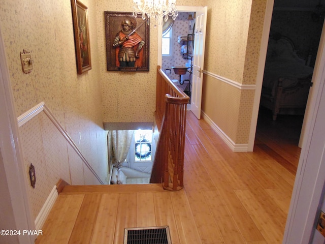 hall featuring wood-type flooring and a chandelier