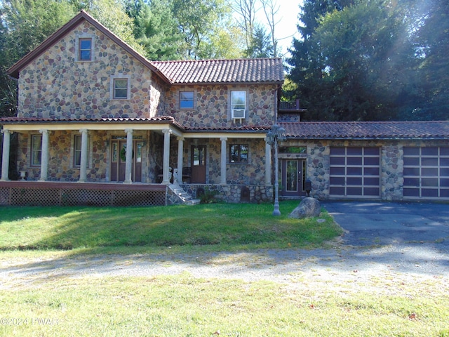 view of front of house with covered porch, a garage, and a front lawn