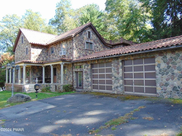 view of front of home featuring cooling unit, a porch, and a garage