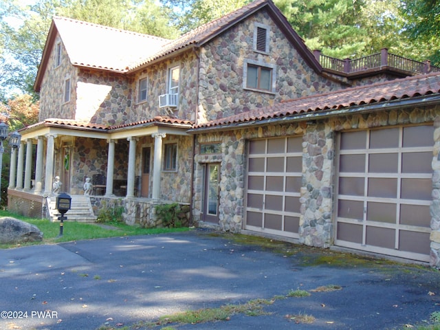 view of front facade featuring a porch, a garage, and cooling unit