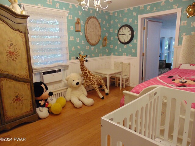 bedroom featuring cooling unit, wood-type flooring, and a notable chandelier