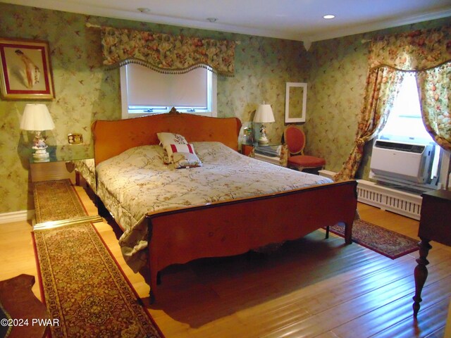 bedroom featuring hardwood / wood-style floors, cooling unit, and radiator