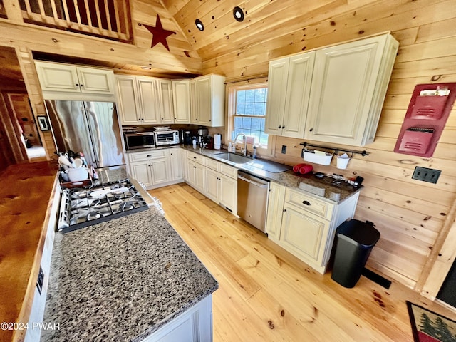 kitchen featuring dark stone counters, sink, stainless steel appliances, and light wood-type flooring