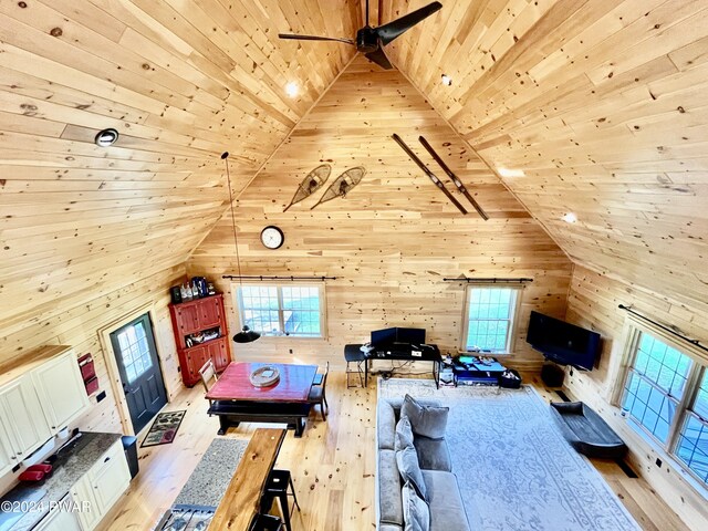 unfurnished living room featuring wood walls, high vaulted ceiling, light hardwood / wood-style flooring, ceiling fan, and wood ceiling