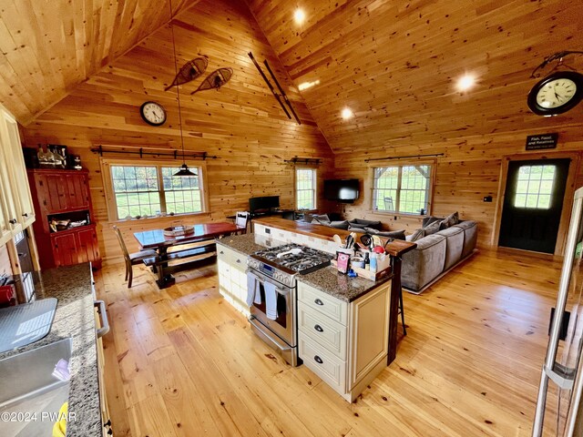 kitchen with pendant lighting, high vaulted ceiling, white cabinets, light hardwood / wood-style floors, and stainless steel range with gas cooktop