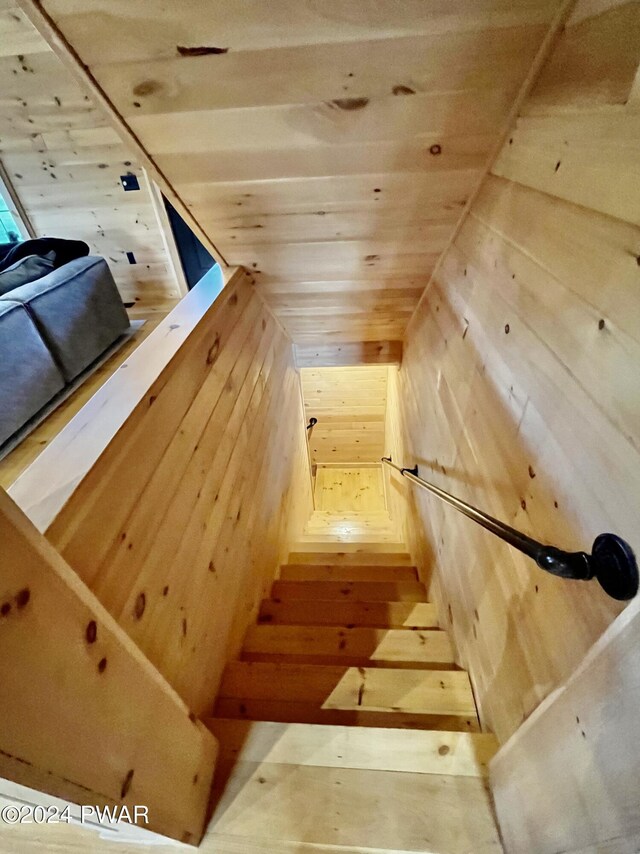 staircase with wood walls and wood ceiling