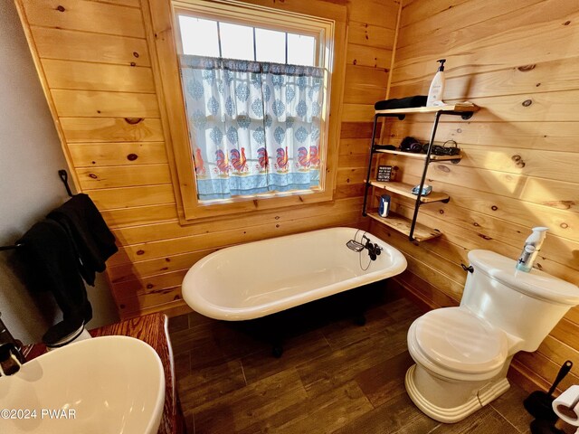 bathroom featuring a tub, wooden walls, hardwood / wood-style floors, and toilet