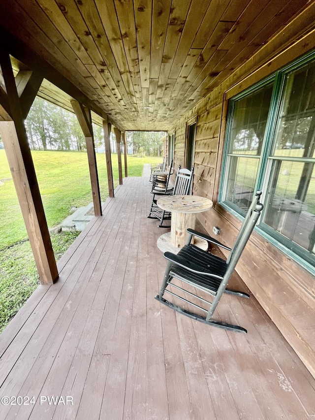 wooden terrace featuring a porch and a yard