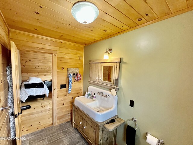 bathroom with wood ceiling, sink, and wooden walls