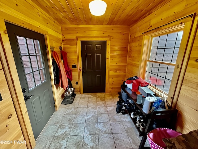 doorway to outside featuring light tile patterned floors, wood walls, and wood ceiling