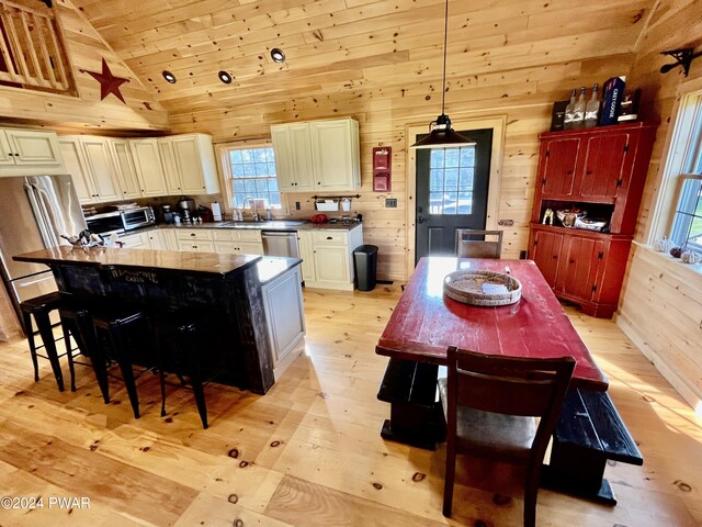 kitchen with light wood-type flooring, wooden ceiling, a center island, hanging light fixtures, and a breakfast bar area