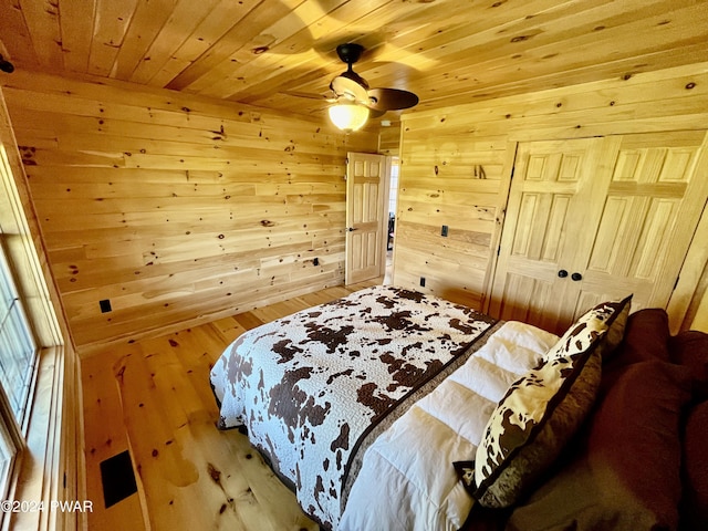 bedroom with ceiling fan, hardwood / wood-style floors, wooden walls, a closet, and wood ceiling