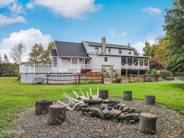 rear view of property featuring a wooden deck, a sunroom, and a yard