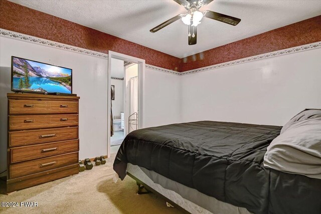 carpeted bedroom featuring ceiling fan and a textured ceiling