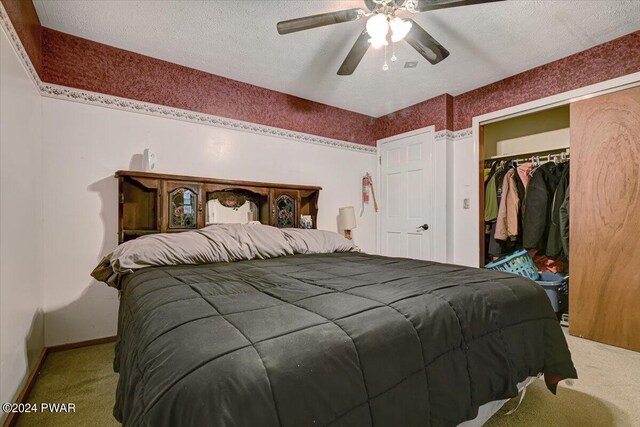 bedroom with carpet, ceiling fan, a textured ceiling, and a closet