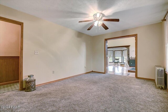 spare room with radiator heating unit, carpet floors, a textured ceiling, and ceiling fan