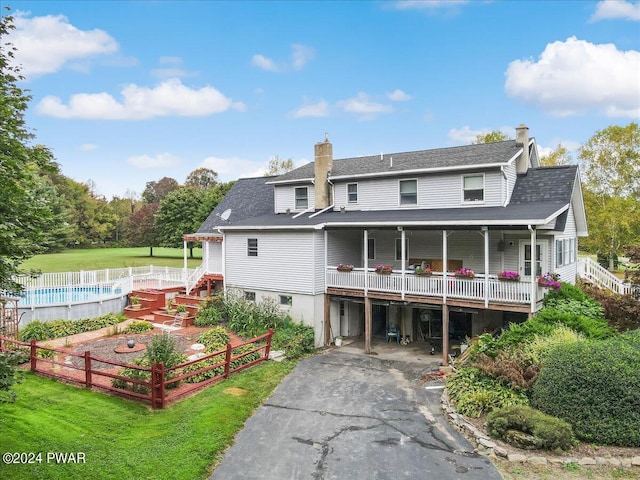 rear view of house featuring a fenced in pool and a lawn