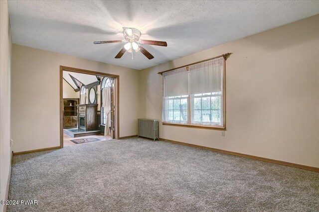 spare room featuring ceiling fan, radiator heating unit, carpet, and a textured ceiling