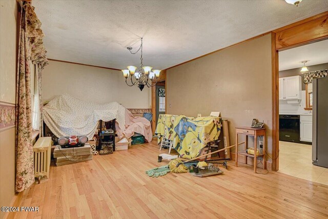 dining room featuring light wood-type flooring, a textured ceiling, radiator, and a notable chandelier