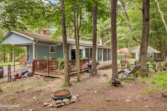 202 Fox Rd, Dingmans Ferry, PA 18328 - rear view of house featuring an outdoor fire pit, a chimney, a wooden deck, and a sunroom