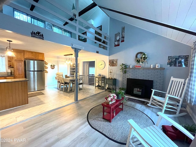 living room with a fireplace, high vaulted ceiling, a chandelier, and light wood-type flooring