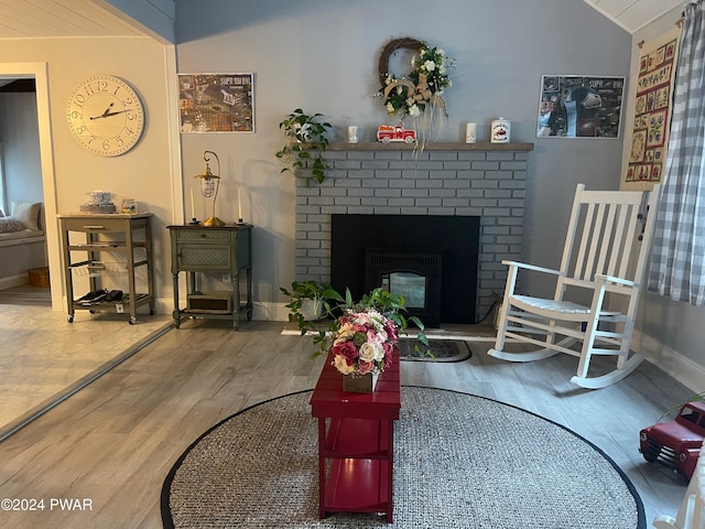 sitting room with a fireplace, wood-type flooring, and vaulted ceiling