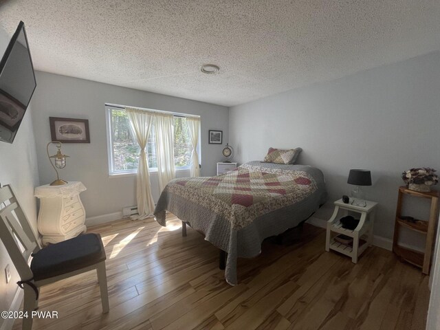 bedroom featuring hardwood / wood-style flooring, a textured ceiling, and a baseboard radiator