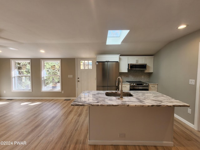 kitchen featuring light stone countertops, appliances with stainless steel finishes, sink, a center island with sink, and white cabinets