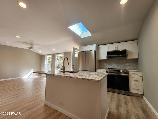 kitchen featuring ceiling fan, sink, vaulted ceiling with skylight, white cabinets, and appliances with stainless steel finishes