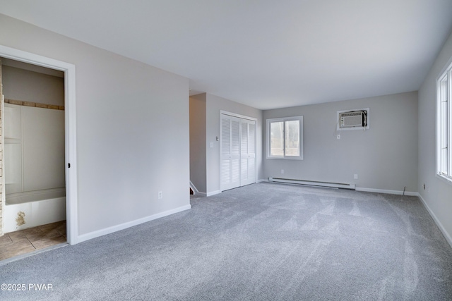 unfurnished bedroom with a wall mounted air conditioner, carpet, connected bathroom, and a baseboard radiator