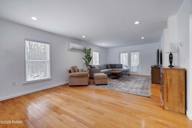 living room with a wall mounted air conditioner and light wood-type flooring