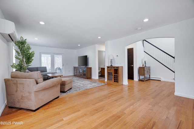 living room featuring baseboard heating, a wall mounted AC, and light wood-type flooring