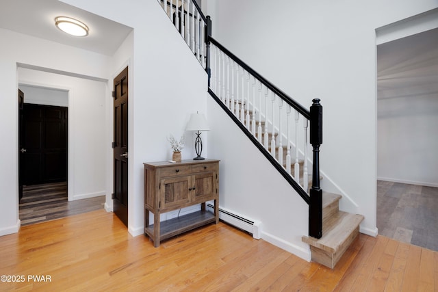 staircase with hardwood / wood-style floors and baseboard heating