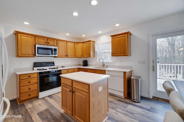 kitchen with sink, hardwood / wood-style floors, white dishwasher, range with gas stovetop, and a kitchen island