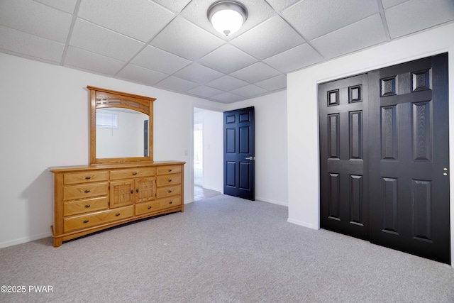 bedroom featuring a paneled ceiling, light carpet, and a closet