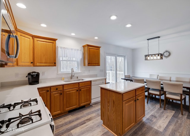 kitchen with pendant lighting, sink, white dishwasher, a healthy amount of sunlight, and a kitchen island