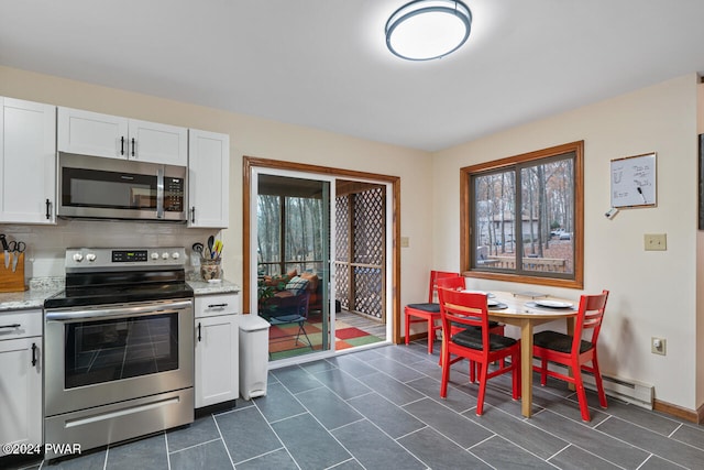 kitchen featuring white cabinets, appliances with stainless steel finishes, tasteful backsplash, and light stone counters