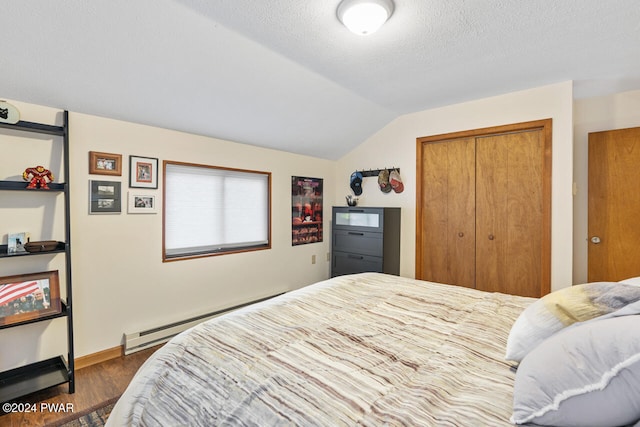 bedroom featuring dark hardwood / wood-style floors, a baseboard heating unit, a textured ceiling, vaulted ceiling, and a closet