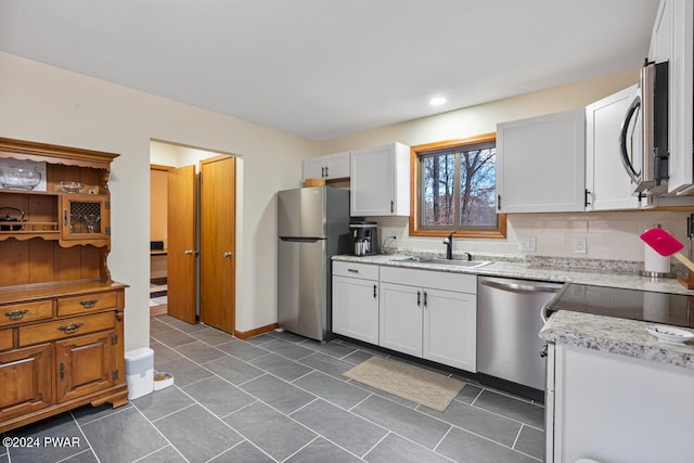 kitchen featuring sink, appliances with stainless steel finishes, tasteful backsplash, light stone counters, and white cabinetry