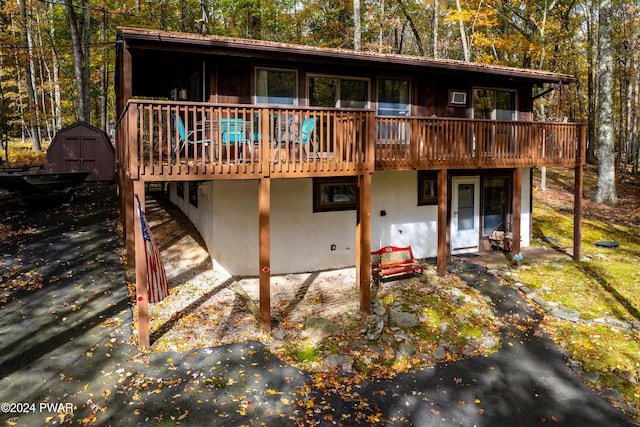 rear view of house with a deck and a storage unit