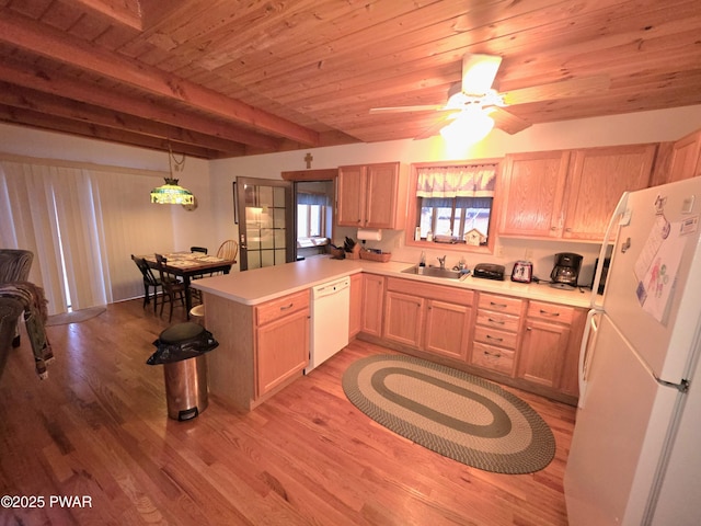 kitchen with a sink, light countertops, white appliances, light wood-style floors, and a peninsula