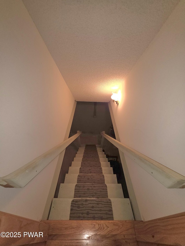staircase featuring a textured ceiling